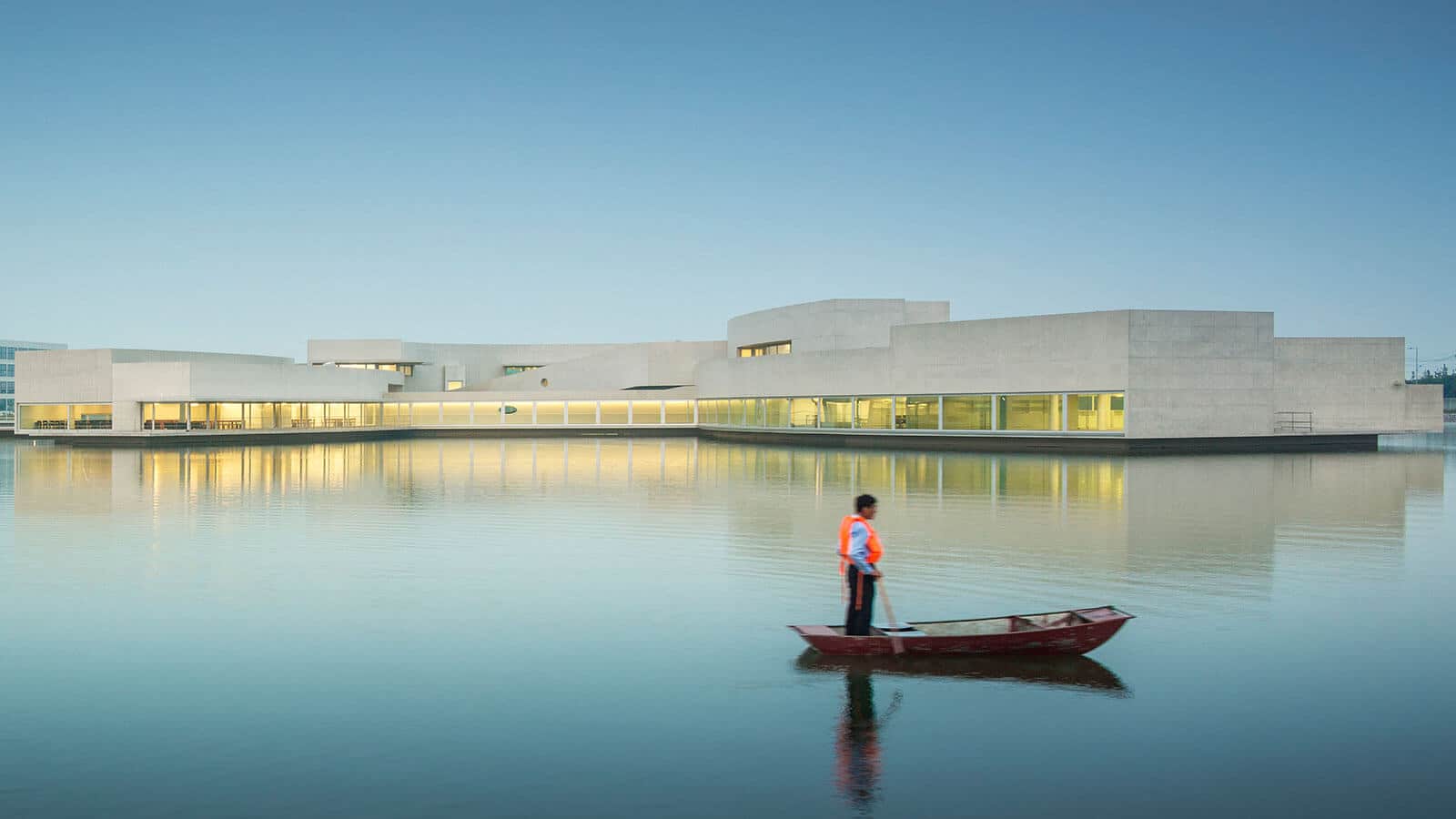 PeterFell-SuperWhite-white-coloured-concrete-building-02 Man in a boat looks at a white concrete building.