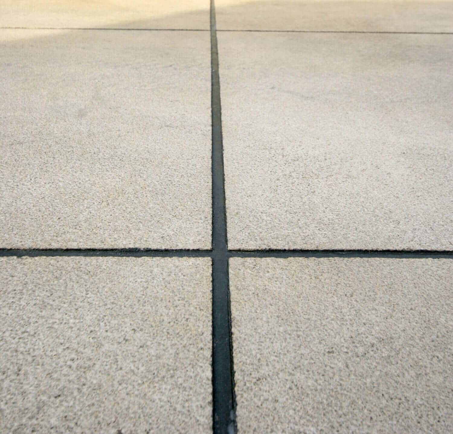 Remove-excess-grout decorative concrete cuts filled with grout.